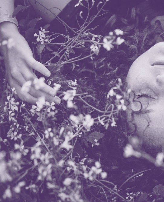 Foto persona acostada pasto con flores con efecto violeta