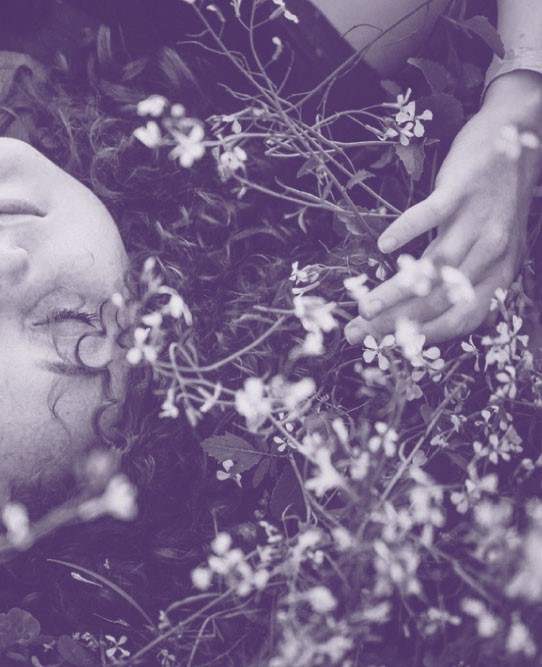 Foto persona acostada pasto con flores con efecto violeta